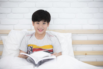 Asian boy rest on the bed and reading book