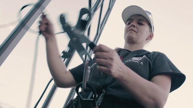 Woman steeplejack uncouples the rope out of her outfit