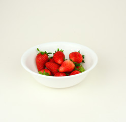 Fresh strawberries with leaf in a white bowl on white background