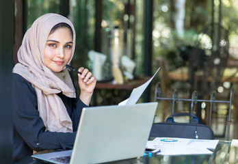 Pretty woman wearing hijab in front of laptop search and doing office work, business, finance and...