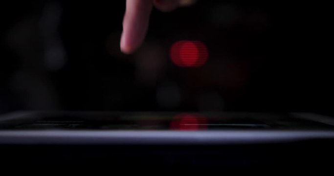 A dramatic closeup with shallow DOF of a finger pressing a button on a touchscreen tablet PC. Profile view, city traffic bokeh in the distance.  	