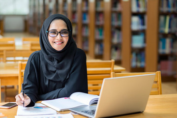 Muslim woman reading book at the library.