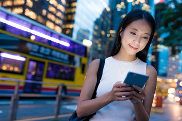 Woman using cellphone in Hong Kong city at night