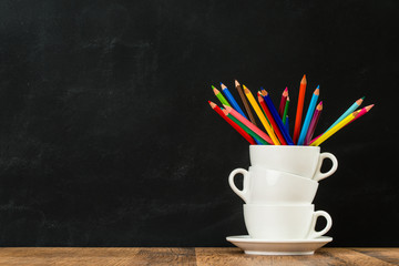 stacked coffee cups with colored pencils