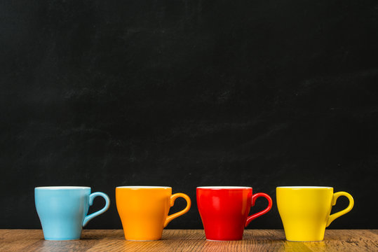 four colored coffee cups on the vintage wood