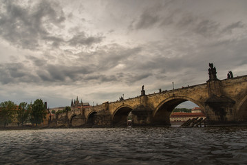 Dramatic Prague Castle with cloudy sunset and Charles Bridge .