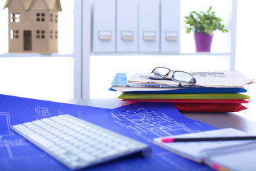 Architectural blueprints and blueprint rolls and a drawing instruments on the worktable