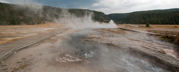 Elevated wooden boardwalk / walkway going past Black Warrior Springs and Tangled Creek and overlooking Hot Lake in the Lower Geyser Basin in Yellowstone National Park in Wyoming United States