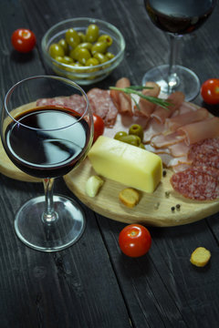 Appetizer on a wooden board with wine and olives for two
