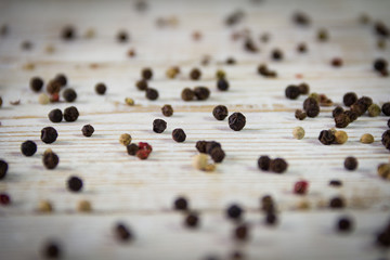 Colorful peppercorns sprinkled on a wooden background. Close-up