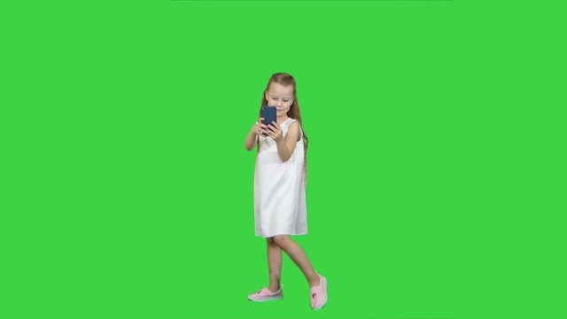 Happy little girl take a selfie with a smart phone on a Green Screen, Chroma Key