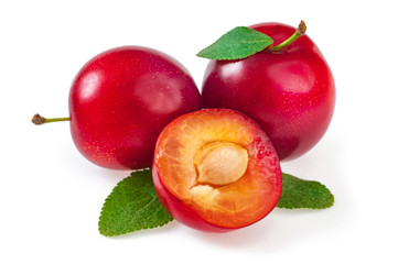 Sweet delicious red plums with leaves, and a juicy plum cut into a half. Close-up, isolated on white