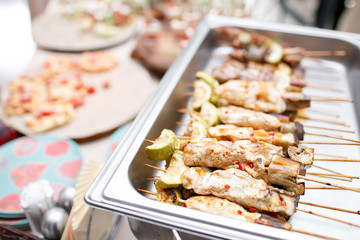 Breakfast buffet in hotel or catering. Grilled chicken on bamboo skewers.