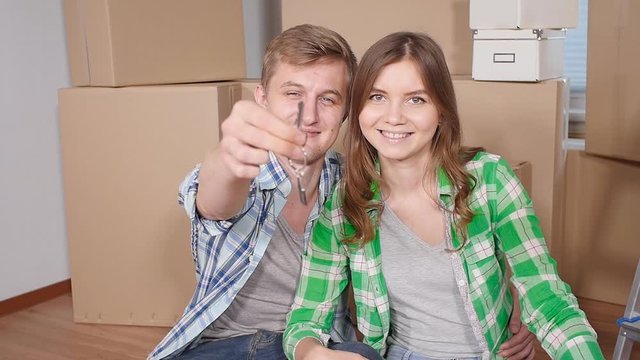Young happy couple with boxes and holding flat keys