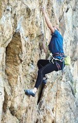 adult woman rock climber. rock climber climbs on a rocky wall. man makes hard move