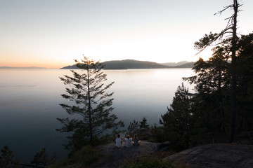 Three people on cliff while Sunset on coast