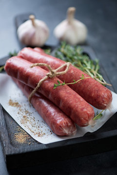 Close-up of raw fresh marbled beef sausages with condiments, shallow depth of field, selective focus