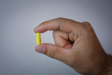Hand holding yellow capsule pill