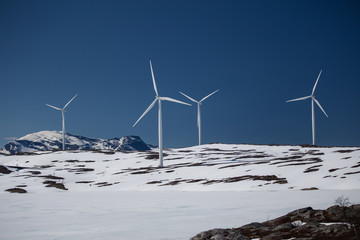 Wind turbines on a snowy hill against clear blue sky in Swedish Lapland