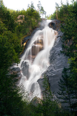 Big waterfall in green forest on sunny day