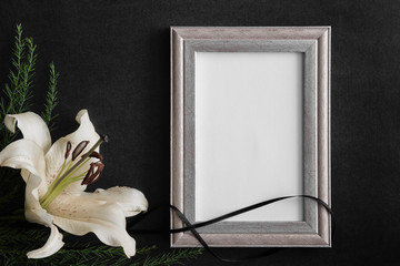 White blank condolence card with frame and lily flower on the dark background. Empty place for a...
