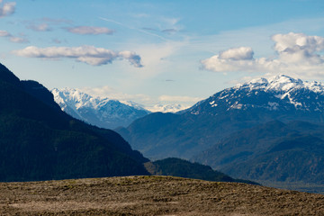 View point from cliff above valley with mountains and clouds.