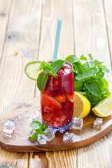 Summer drink with raspberries, lime and ice on a old wooden table