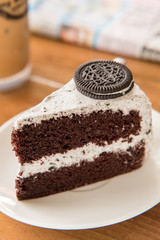 Chocolate Cake with oreo and whipped cream on white plate and wood table has ready to served.