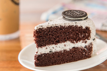 Chocolate Cake with oreo and whipped cream on white plate and wood table has ready to served.