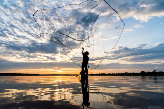 Silhouette of Fishermen throwing net fishing in sunset time at Wanon Niwat district Sakon Nakhon Northeast Thailand.