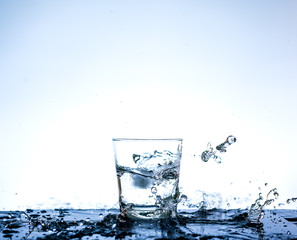 Water splashing in the glass with reflection on mirror.