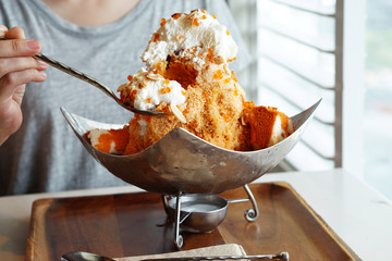 Thai Tea Shaved Ice served with bread, whipped cream, smaller spheres of white and orange boba...