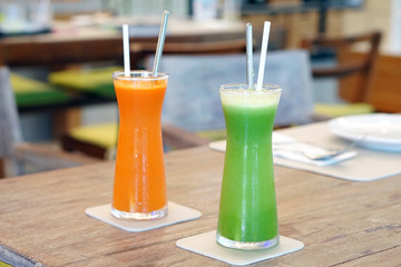 Closeup glass of cold pressed juice on wooden table, Fresh mixed fruits made from carrot, passion, fruit, cantaloupe, wolfberry, gotu kola,curcuma, guava and pineapple, Healthy drink concept.