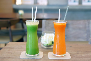 Closeup glass of cold pressed juice on wooden table, Fresh mixed fruits made from carrot, passion, fruit, cantaloupe, wolfberry, gotu kola,curcuma, guava and pineapple, Healthy drink concept.