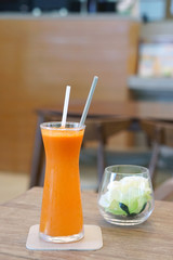 Closeup glass of cold pressed juice on wooden table, Fresh mixed fruits (carrot, passion, fruit, cantaloupe, wolfberry) - Healthy drink concept.