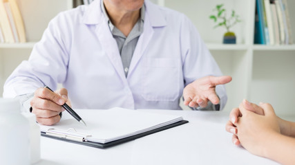 patient listening intently to a male doctor explaining patient symptoms or asking a question as they discuss paperwork together in a consultation