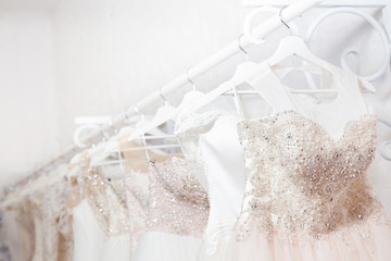 Copy space Wedding dresses for the bride on hangers against a white background of brick in the store. Concept wedding, engagement, attributes, clothing, love.