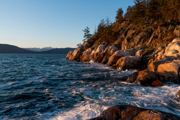 Fototapeta na wymiar Ocean waves hitting rocks on coast while sunset