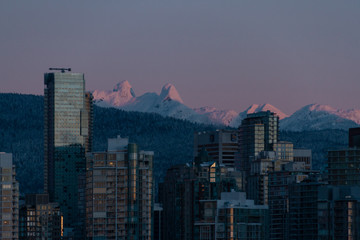 Obraz premium Winter cityscape with mountains and sunrise illuminating building