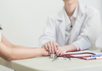 Fototapeta premium Hand of doctor reassuring her female patient in the consulting room.