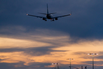 Fototapeta na wymiar Plane flying low over parking lot while sunset