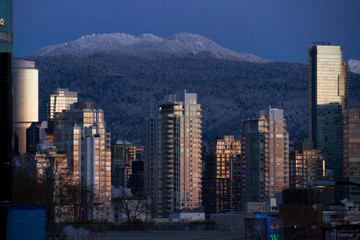 Winter cityscape with mountains and sunrise illuminating building