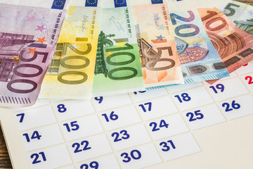Vacation money on the background of the calendar. Holiday planning. Euro banknotes.