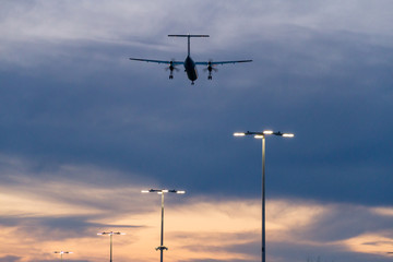 Plane flying low over parking lot while sunset
