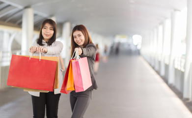 Soft focus On Bags. Beautiful two asian woman with shopping bags walking on the street.