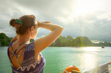 Woman traveler on the boat, enjoying view of the island at sunset