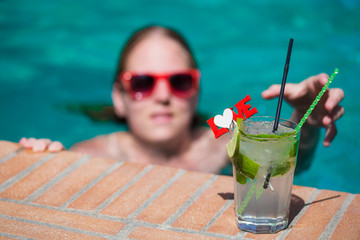 Young female in swimming pool with cocktail