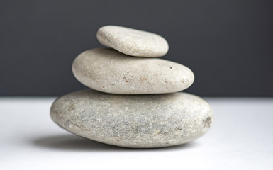 Fototapeta na wymiar Stones pyramid on white table and black background, balanced stones pyramid for meditation and relax