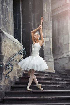 Full length shot of a beautiful young female ballet dancer posing gracefully on the stairway of an old building in the city.