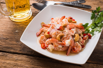 Spicy salad prawn with lemon grass in white plate with mug of beer 